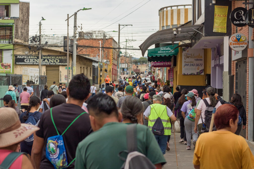 Caminata Tres Esquinas en Fusagasugá: Crónica, Ruta y Fotos (2026) 23 Senderistas descendiendo por calle comercial de Fusagasuga pasando por floristerias locales