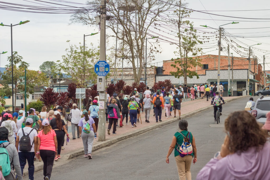 Caminata Tres Esquinas en Fusagasugá: Crónica, Ruta y Fotos (2026) 24 Senderistas y ciclista avanzando por avenida pavimentada hacia Villa Natalia en Fusagasuga