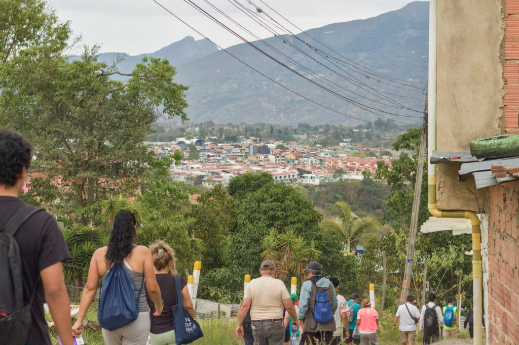 Caminata Tres Esquinas en Fusagasugá: Crónica, Ruta y Fotos (2026) 27 Senderistas caminando por berma verde con vista panoramica de Fusagasuga y montanas