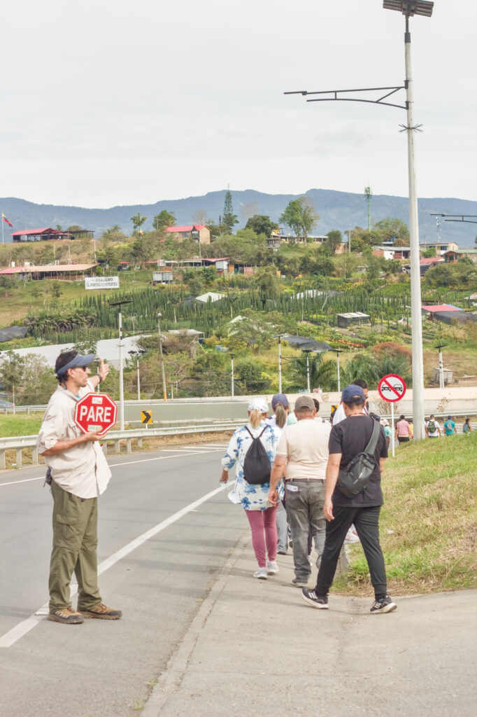 Caminata Tres Esquinas en Fusagasugá: Crónica, Ruta y Fotos (2026) 37 Guia de la Secretaría de Cultura y Turismo deteniendo vehículos en la Variante Panamericana de Fusagasuga con paleta PARE