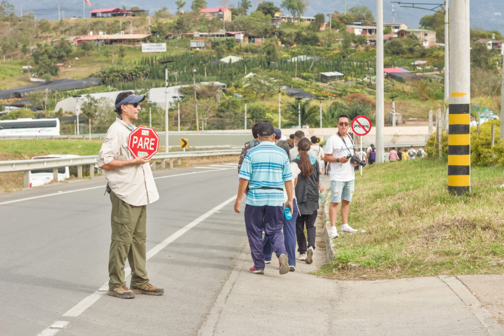 Caminata Tres Esquinas en Fusagasugá: Crónica, Ruta y Fotos (2026) 38 Fotografo documentando la caminata junto a guia vial con paleta PARE en la Variante de Fusagasuga