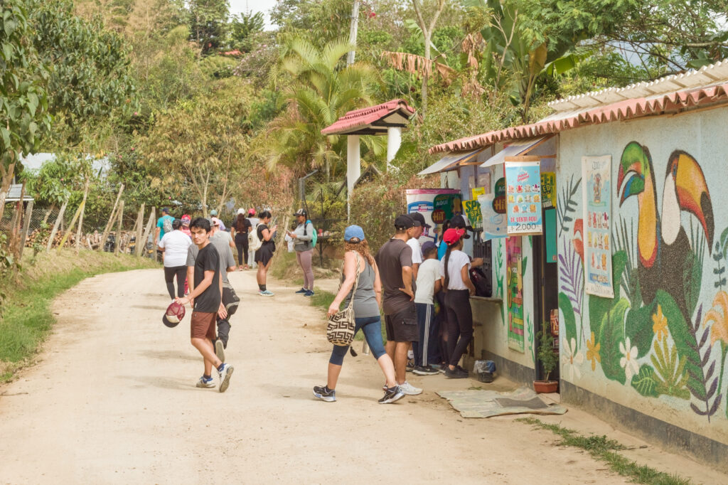 Caminata Tres Esquinas en Fusagasugá: Crónica, Ruta y Fotos (2026) 50 Caminantes comprando agua y paletas en tienda rural con mural de tucan en Vereda Cucharal Fusagasuga