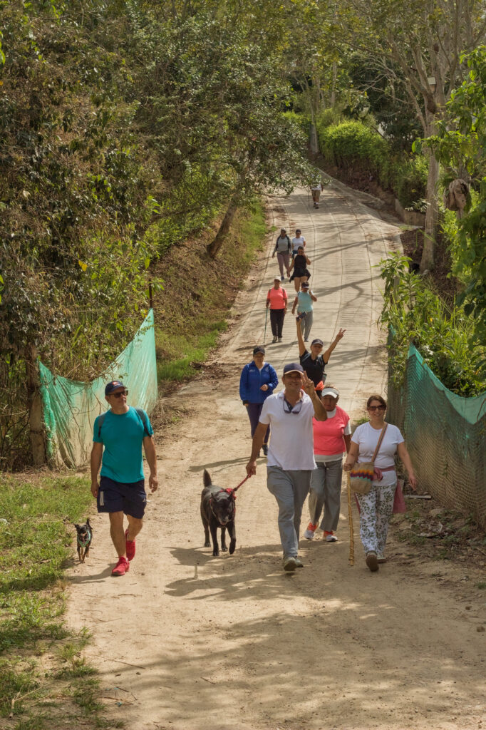 Caminata Tres Esquinas en Fusagasugá: Crónica, Ruta y Fotos (2026) 55 Senderista con polo blanco y perro negro con correa bajando pendiente empinada en Novillero Fusagasuga