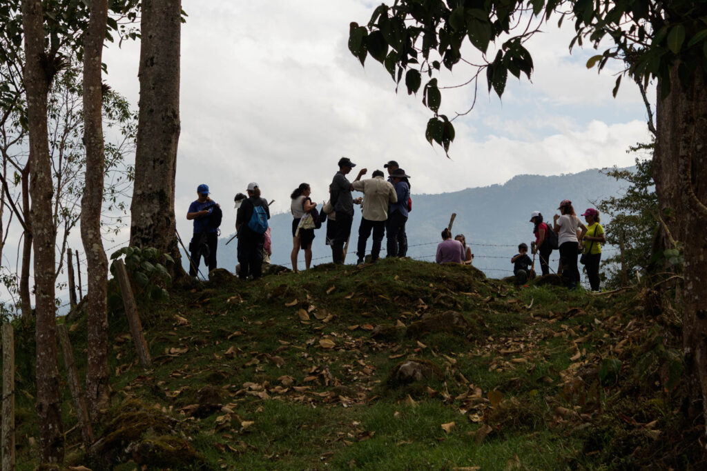 Tras las huellas de los Sutagaos: Una travesía ancestral por el camino La Palma - La Aguadita 33 Senderistas bajando por colina de pasto verde hacia La Aguadita